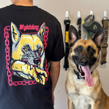 A person wearing a black t-shirt with a graphic design of a dog on it, standing next to a dog with its tongue out.
