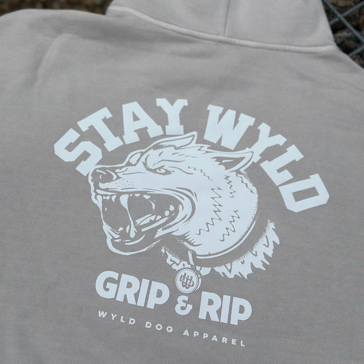 A gray hoodie with the 'STAY WYLD' logo and text 'GRIP & RIP' on the back, featuring a stylized dog head.